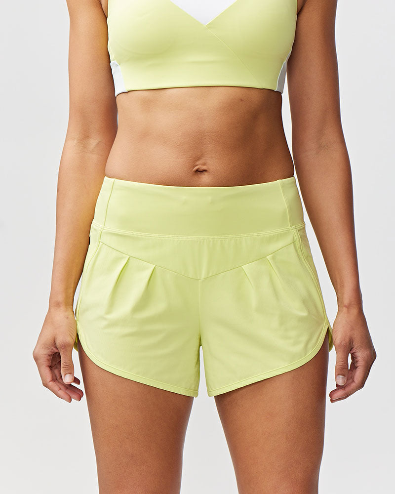 Person wearing a light green sports bra and shorts on a plain background