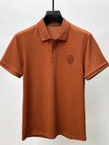 Brown polo shirt with a logo on a hanger against a white background