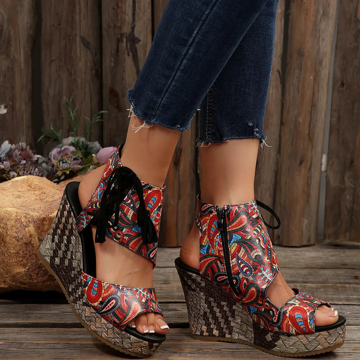 Colorful patterned sandals worn with blue jeans against a wooden background