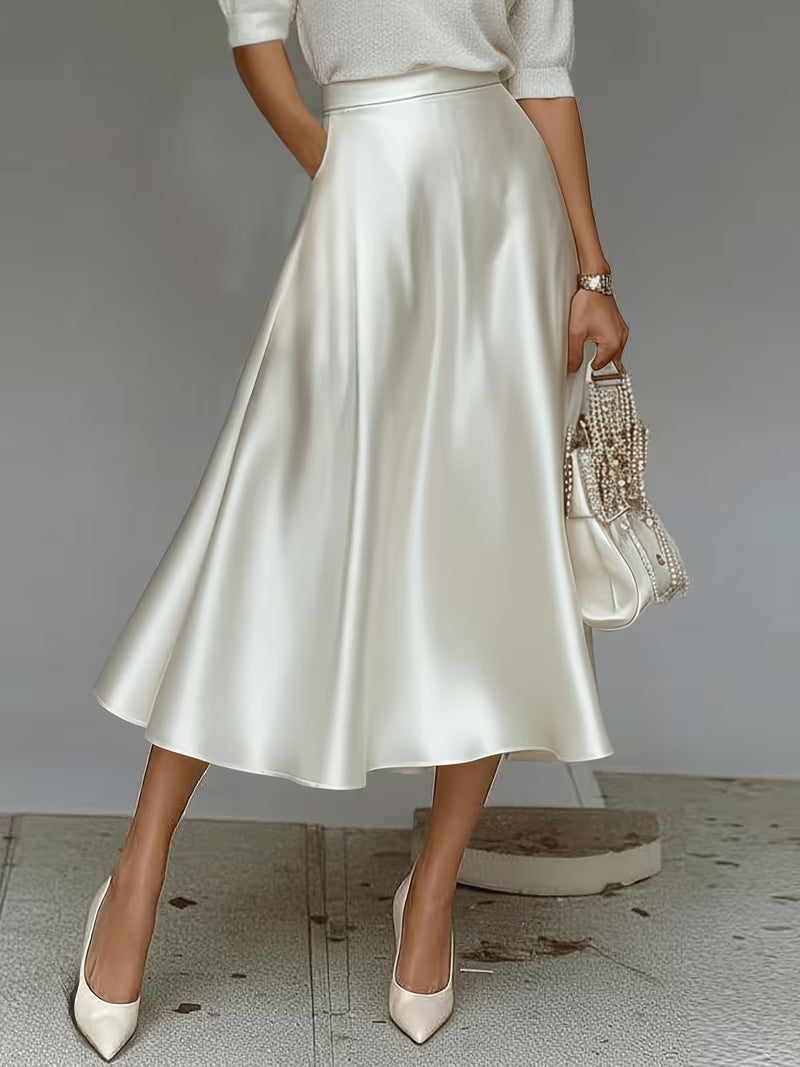 Person wearing a white satin skirt with a plain background