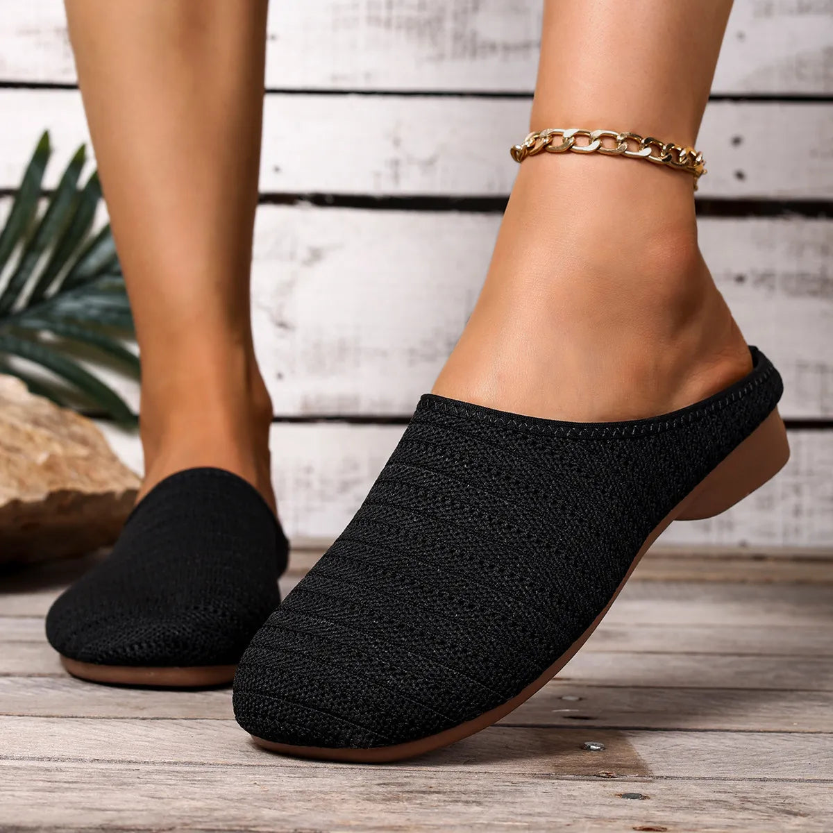 Black slip-on shoes worn with a wooden floor background
