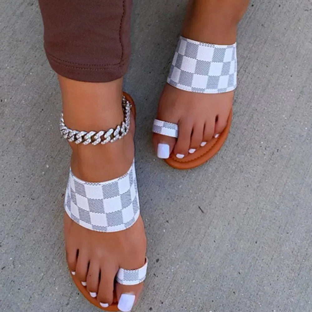Brown sandals with checkered straps worn on a concrete surface