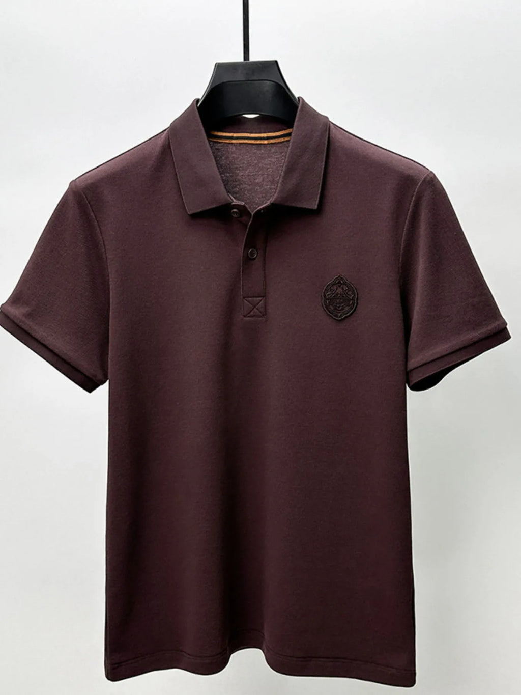 Brown polo shirt on a hanger against a white background