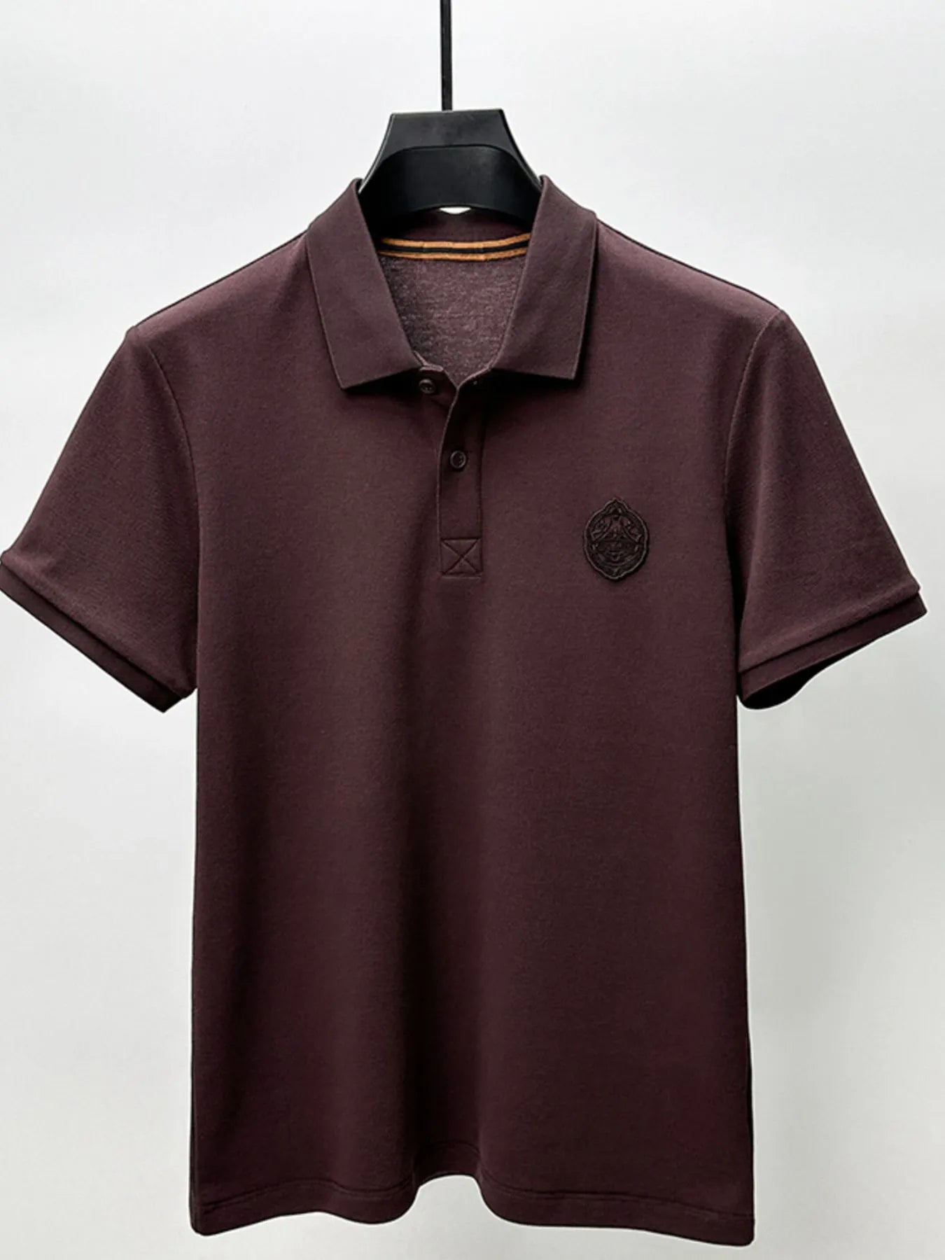 Brown polo shirt on a hanger against a white background