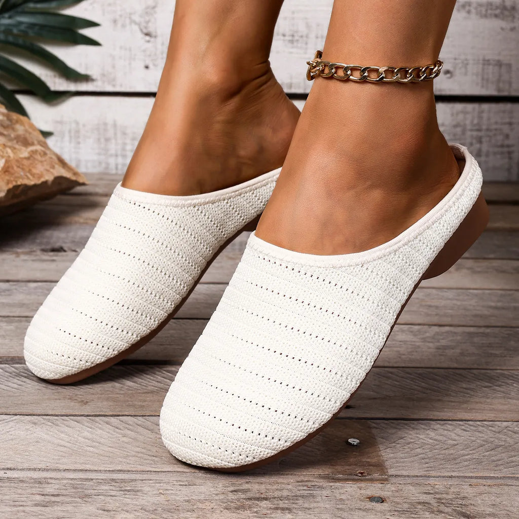 White textured slippers worn on a wooden floor with a neutral background