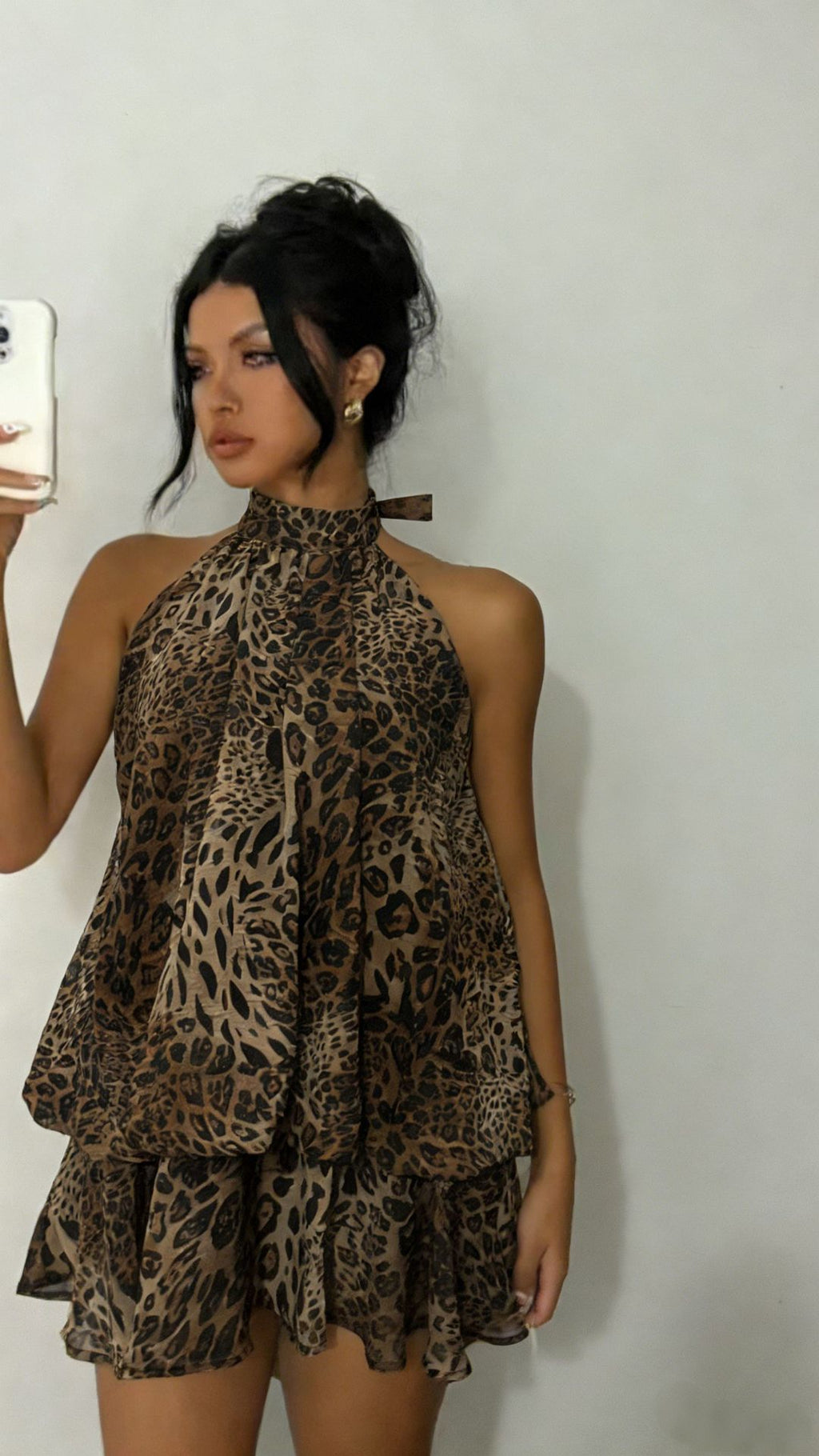 Woman wearing a leopard print dress against a plain background
