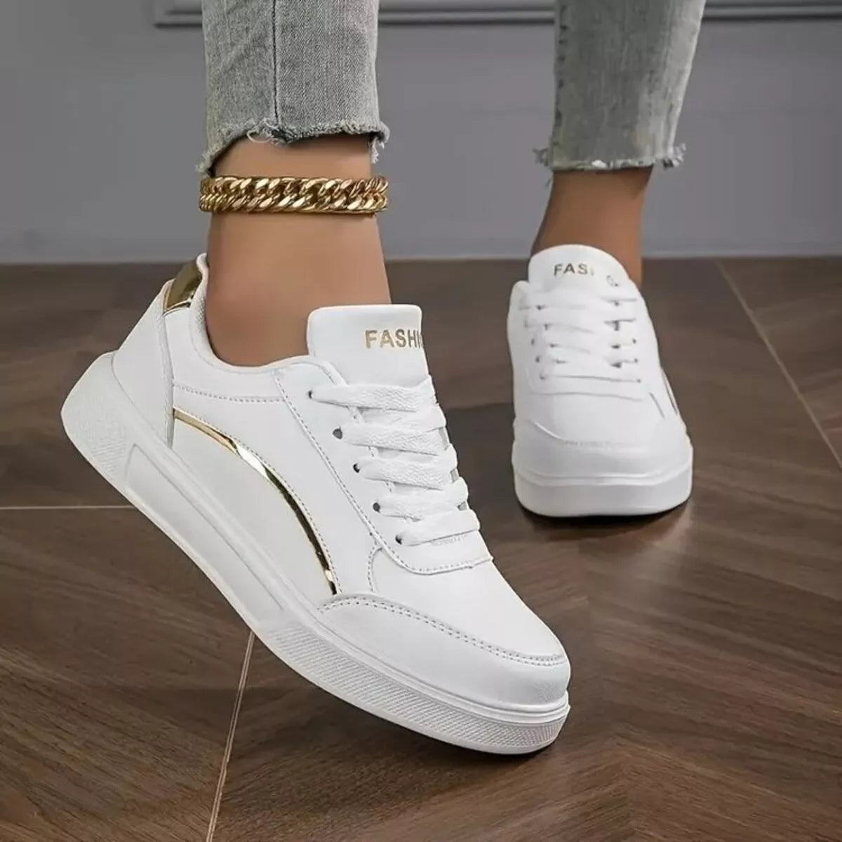 White sneakers with gold accents worn by a person on a wooden floor-blackorvani.com