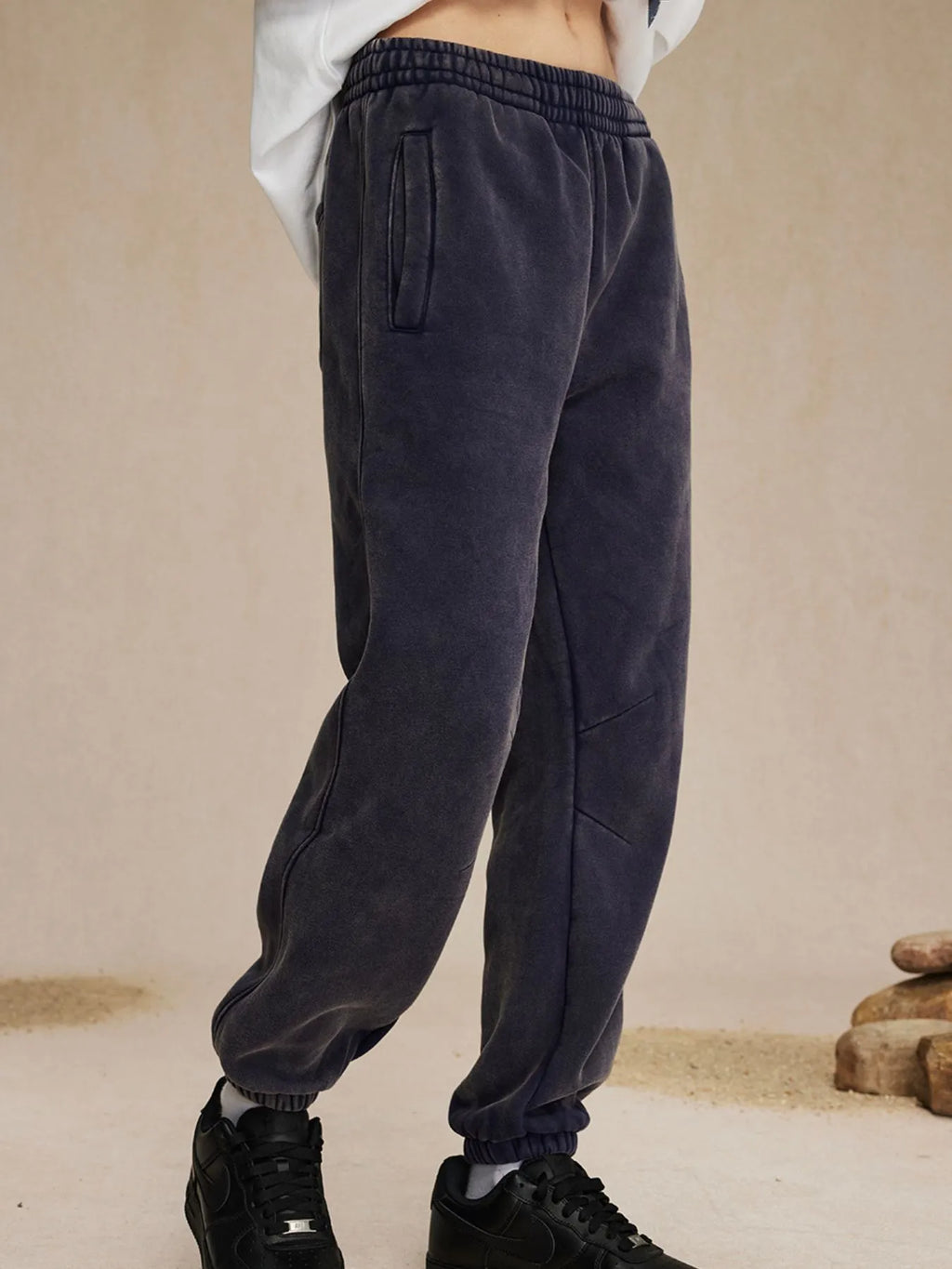 Dark gray sweatpants worn by a person on a beige background-blackorvani.com