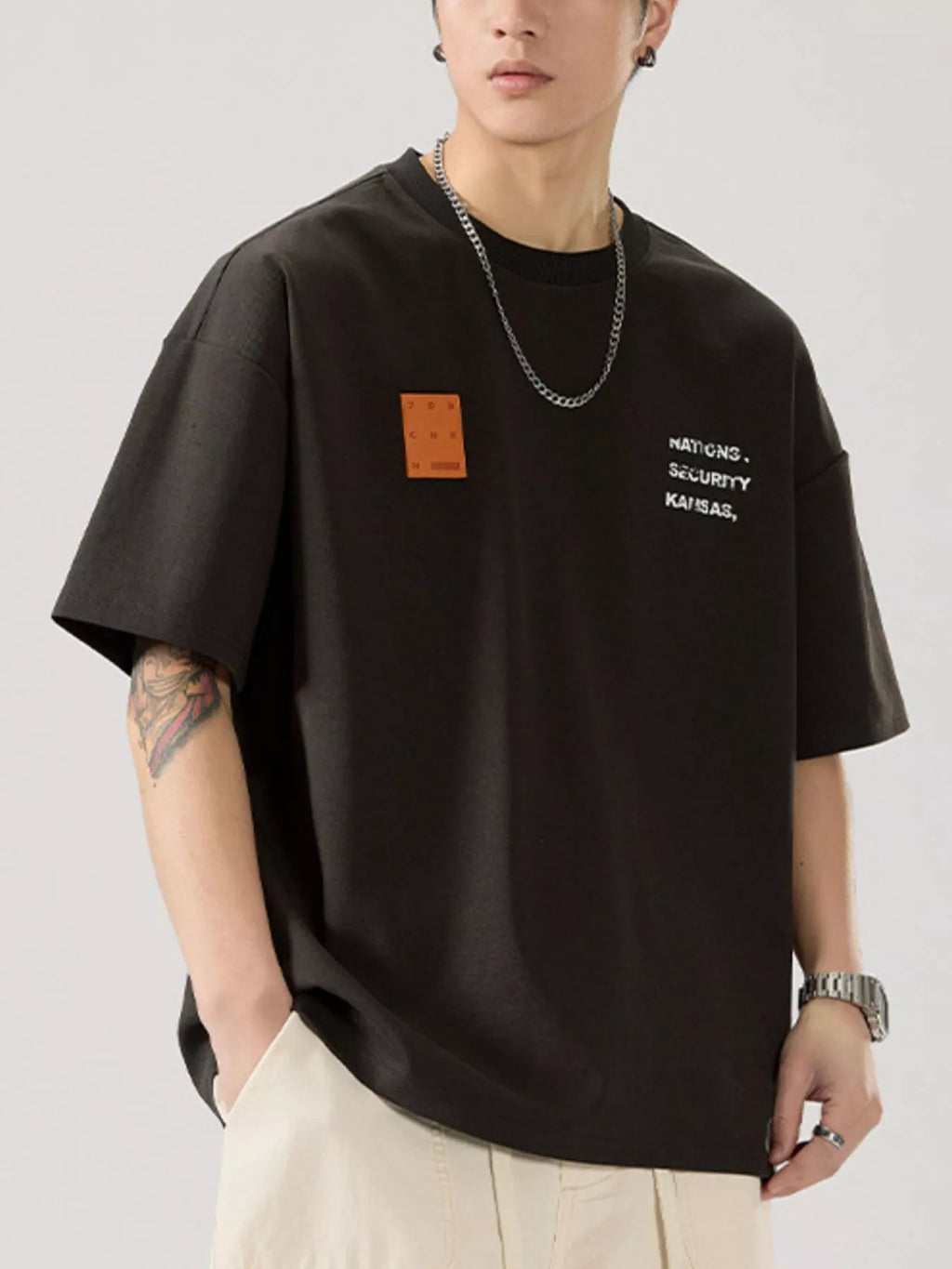 men wearing a black t-shirt with text and a patch on a plain background