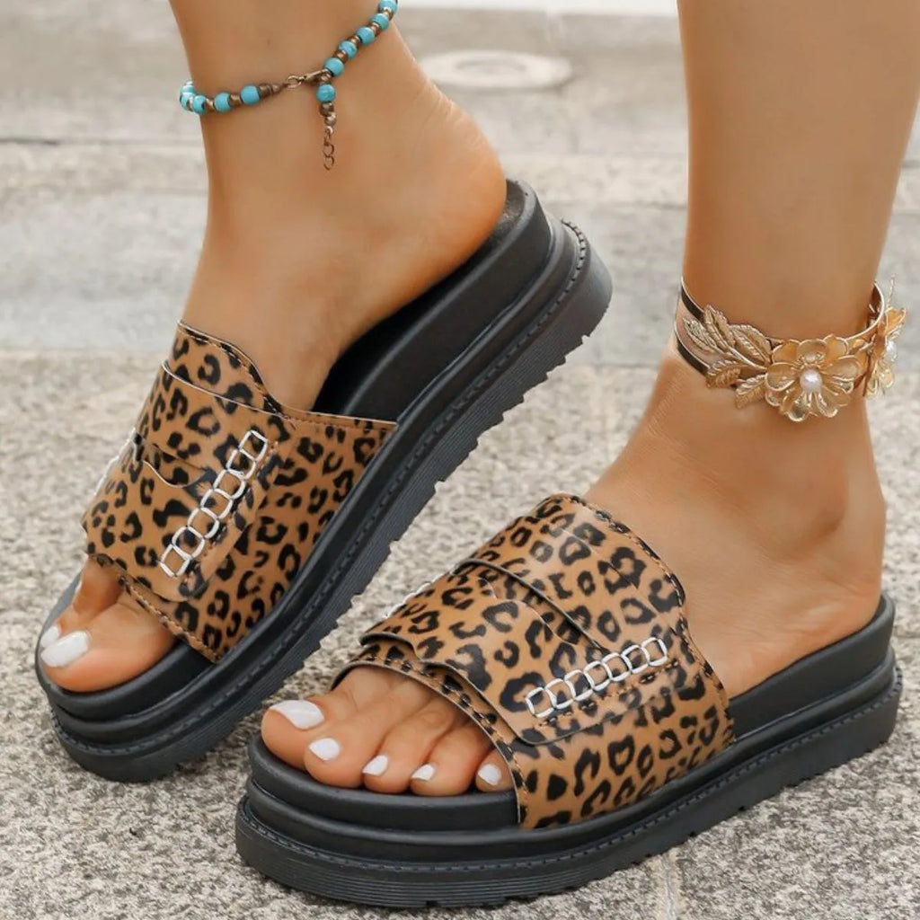 Leopard print sandals worn on feet with a neutral background