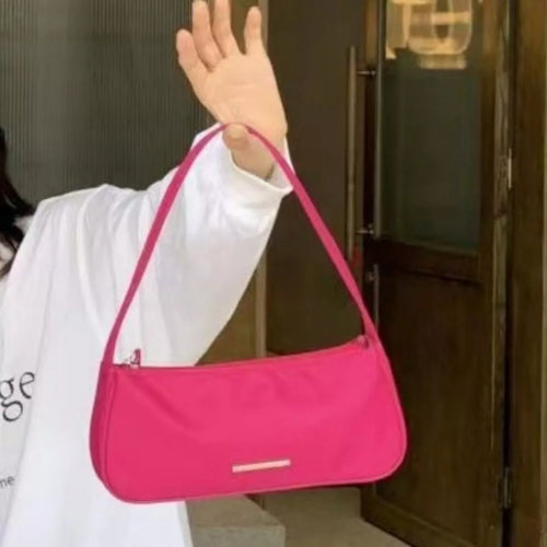 Person holding a pink handbag in front of a wooden door-blackorvani