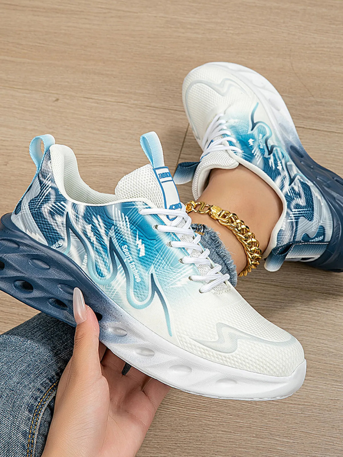 White sneakers with blue accents worn by a person on a wooden floor