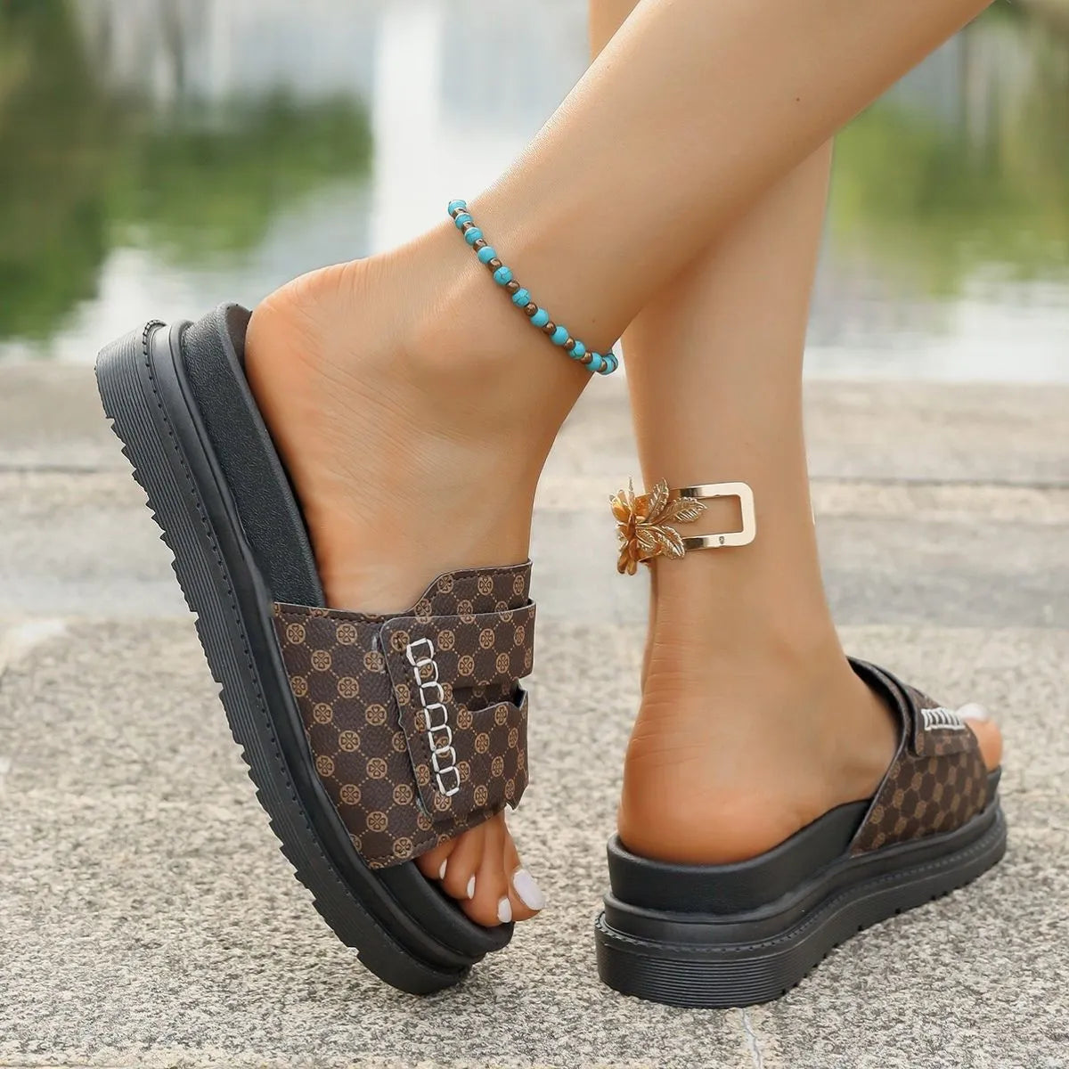 Brown patterned sandals with black platforms worn by a person on a blurred outdoor background