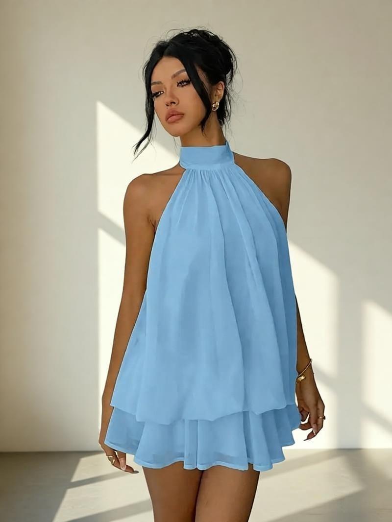 Woman wearing a light blue halter neck dress in a bright room.