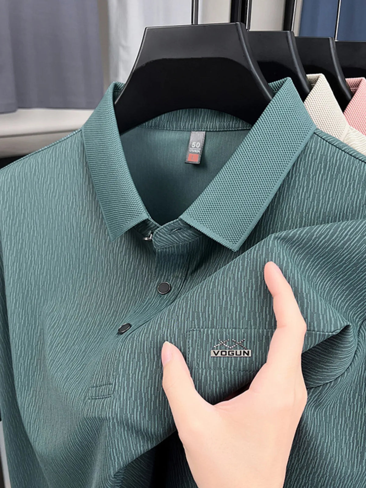 Green polo shirt on a hanger with a hand touching it, brand 'Vogun' visible-blackorvani.com
