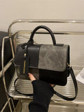 Black and gray handbag held by a person on a metal surface-Black Orvani