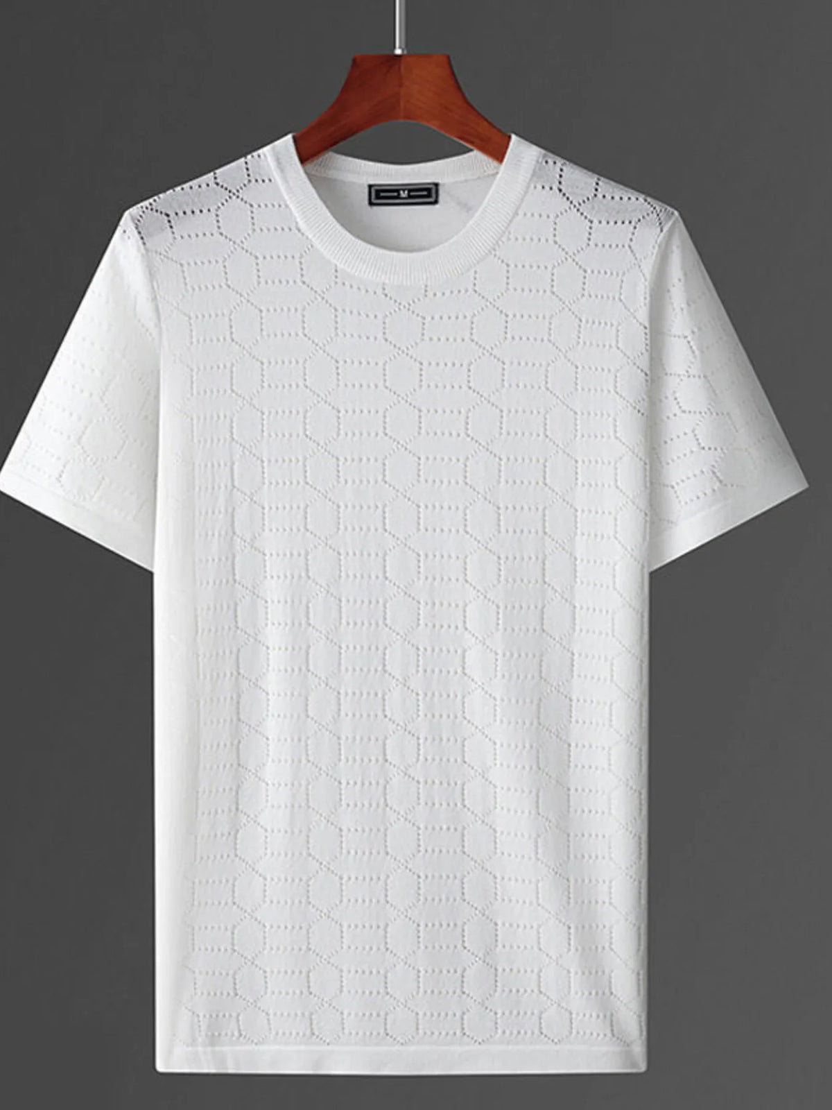 White textured t-shirt on a wooden hanger against a dark background