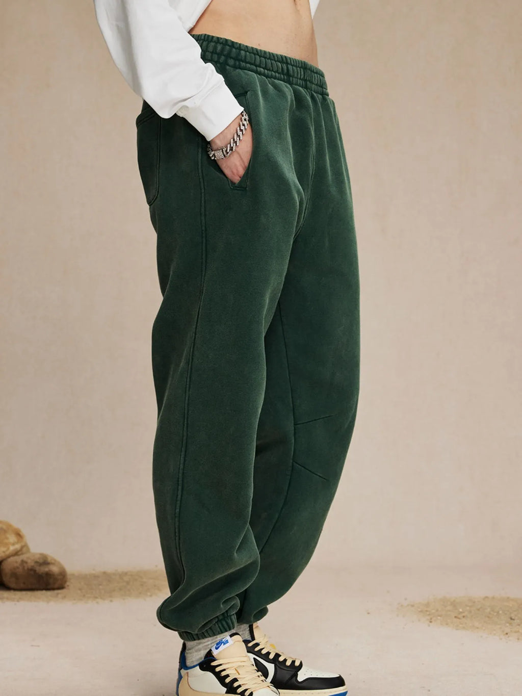 Green sweatpants worn by a person on a beige background-blackorvani.com