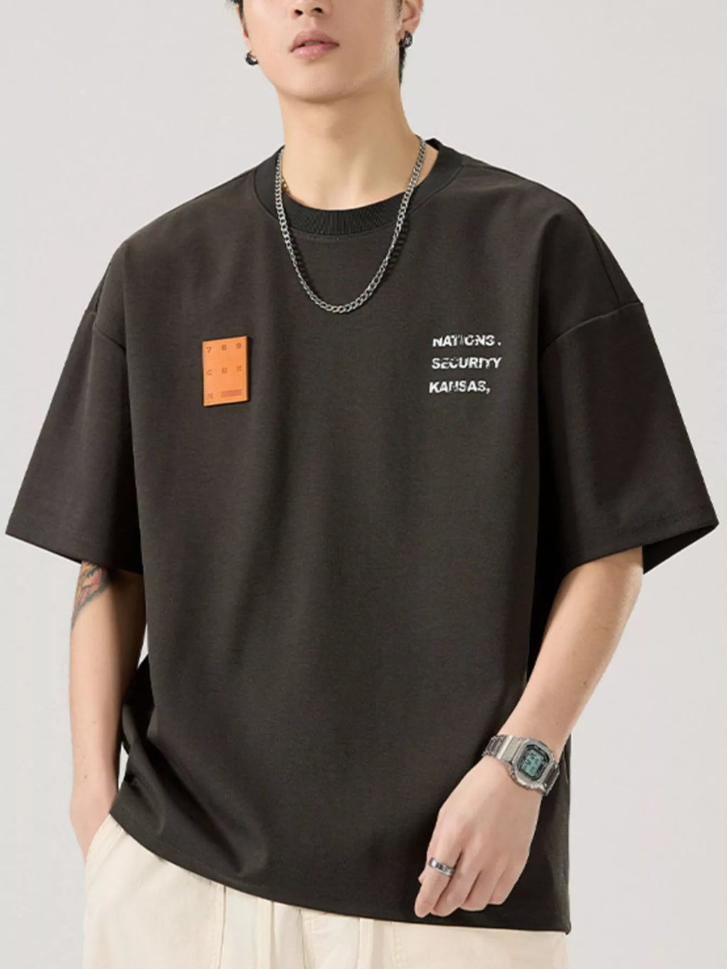 men wearing a black t-shirt with text and a patch on a plain background