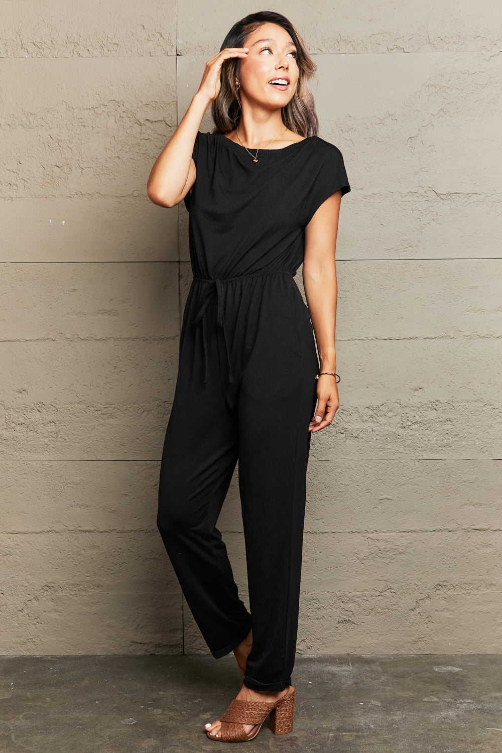 Woman wearing a black jumpsuit against a beige wall-BlackOrvani