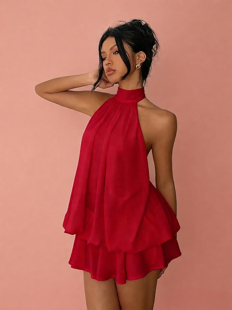 Woman wearing a red halter dress against a pink background