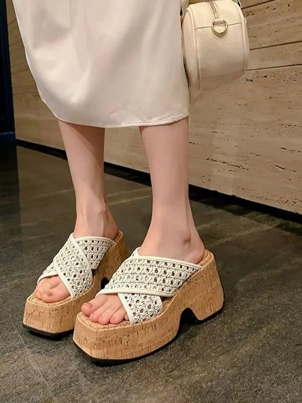 White platform sandals with cork sole worn by a person, holding a beige handbag-blackorvani.com
