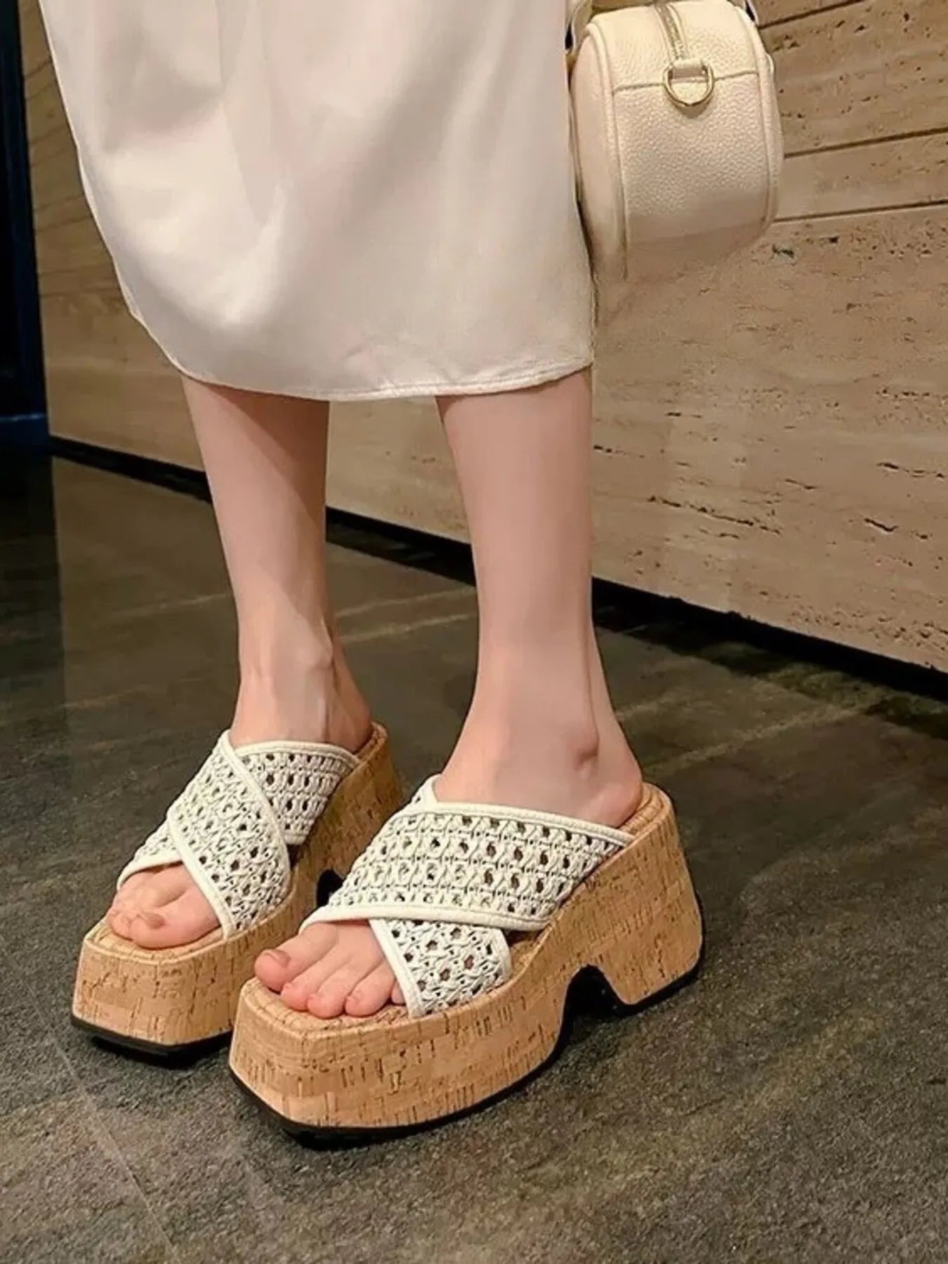 White platform sandals with cork sole worn by a person, holding a beige handbag-blackorvani.com